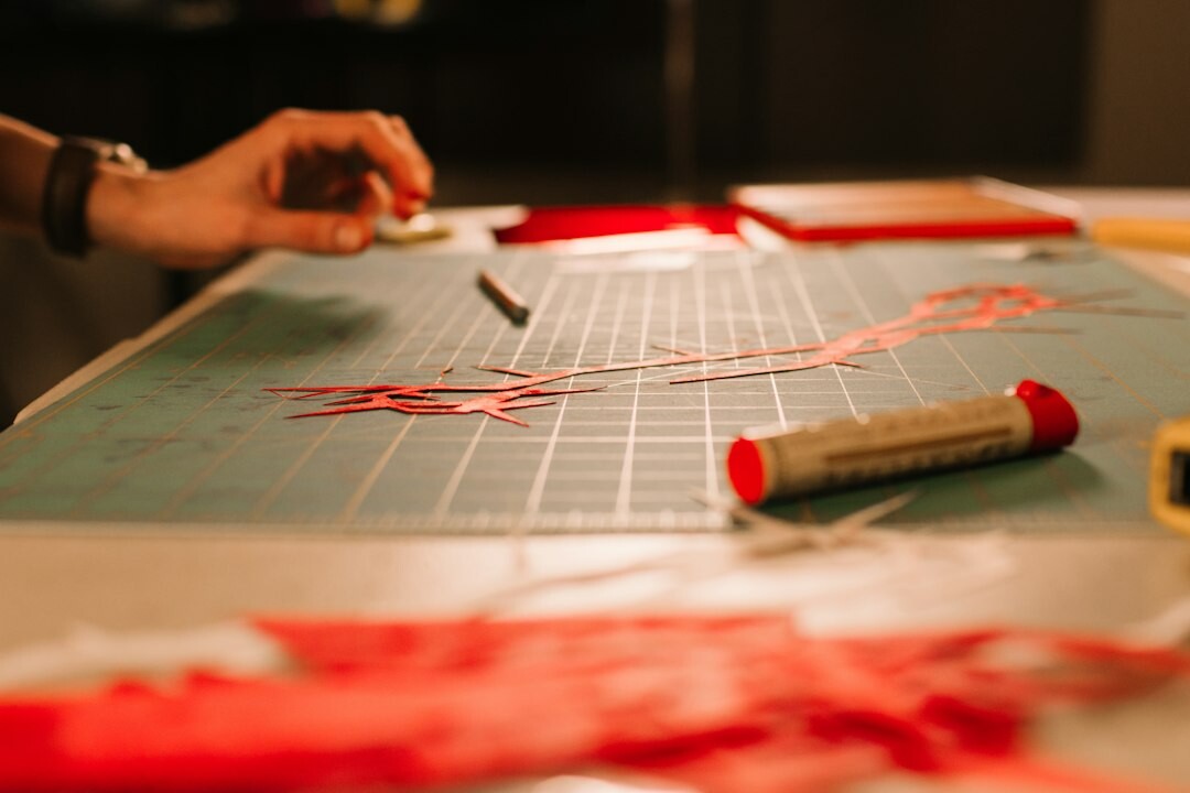 Close-up of hands pinning red threads and photographs on a crime investigation board